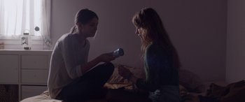 Movie still from “Breathe” (2014), directed by Mélanie Laurent – Two women sitting on a bed looking at a cell phone; Medium shot, Over the shoulder angle