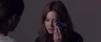 Movie still from “Breathe” (2014), directed by Mélanie Laurent – A woman holding a can in one hand and a cell phone in the other hand; Close Up shot, Over the shoulder angle