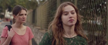 Movie still from “Breathe” (2014), directed by Mélanie Laurent – A young woman in a green lace dress is standing next to a fence; Close Up shot, Over the shoulder angle