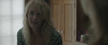 Movie still from “Breathe In” (2013), directed by Drake Doremus – A woman with long blonde hair sitting in front of a wooden door; Close Up shot, Over the shoulder angle