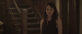 Movie still from “Breathe In” (2013), directed by Drake Doremus – A woman standing in front of some stairs; Close Up shot, Over the shoulder angle
