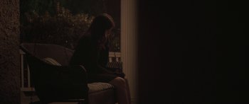 Movie still from “Breathe In” (2013), directed by Drake Doremus – A woman sitting on a chair in a dark room; Wide shot, High angle