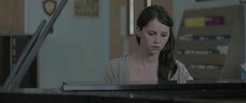 Movie still from “Breathe In” (2013), directed by Drake Doremus – A woman sitting in front of a piano looking sad; Close Up shot, Over the shoulder angle