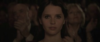 Movie still from “Breathe In” (2013), directed by Drake Doremus – A person with a crowd in the background; Close Up shot, Over the shoulder angle