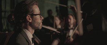 Movie still from “Breathe In” (2013), directed by Drake Doremus – A man with glasses is looking at a person playing the violin; Close Up shot, Low angle