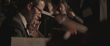 Movie still from “Breathe In” (2013), directed by Drake Doremus – A man is playing the violin in a orchestra; Extreme Close Up shot, Low angle