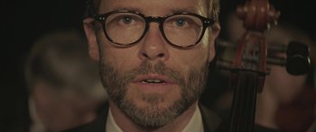 Movie still from “Breathe In” (2013), directed by Drake Doremus – A person wearing glasses and a suit; Extreme Close Up shot, Low angle