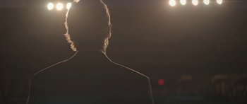 Movie still from “Breathe In” (2013), directed by Drake Doremus – A man with a beard is standing in front of a spotlight; Close Up shot, Low angle