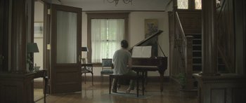 Movie still from “Breathe In” (2013), directed by Drake Doremus – A man sitting in front of a piano in a living room; Wide shot, Low angle