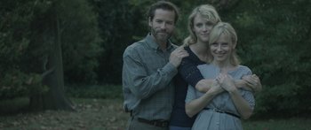 Movie still from “Breathe In” (2013), directed by Drake Doremus – A man and two women posing for a picture; Medium shot, High angle
