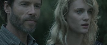 Movie still from “Breathe In” (2013), directed by Drake Doremus – A man and a woman standing next to each other in front of trees; Close Up shot, Over the shoulder angle