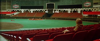 Movie still from “Brewster McCloud” (1970), directed by Robert Altman – An empty baseball stadium with red seats and green grass; Extreme Wide shot, High angle