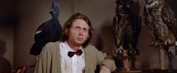 Movie still from “Brewster McCloud” (1970), directed by Robert Altman – A man sitting in front of a statue of an owl; Close Up shot, Low angle