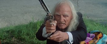 Movie still from “Brewster McCloud” (1970), directed by Robert Altman – An old man with a white beard holding a gun in his hand; Close Up shot, Low angle