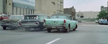Movie still from “Brewster McCloud” (1970), directed by Robert Altman – Two cars are driving down the street in the city; Wide shot, Low angle