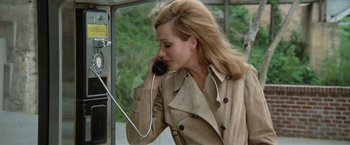 Movie still from “Brewster McCloud” (1970), directed by Robert Altman – A woman talking on a phone while wearing a trench coat; Close Up shot, High angle