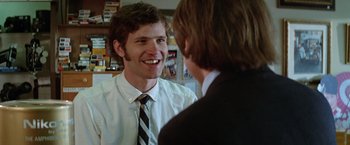 Movie still from “Brewster McCloud” (1970), directed by Robert Altman – A man wearing a suit and tie talking to another man wearing a suit and tie; Close Up shot, Over the shoulder angle