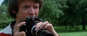 Movie still from “Brewster McCloud” (1970), directed by Robert Altman – A man holding a camera up to his face; Close Up shot, Low angle