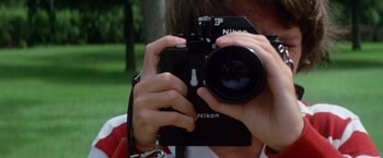 Movie still from “Brewster McCloud” (1970), directed by Robert Altman – A person taking a picture with a camera; Extreme Close Up shot, Low angle