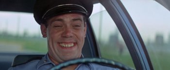 Movie still from “Brewster McCloud” (1970), directed by Robert Altman – A man in a police uniform smiling in the driver's seat of a car; Close Up shot, Low angle