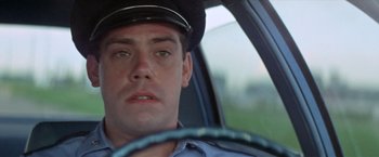 Movie still from “Brewster McCloud” (1970), directed by Robert Altman – A police officer sitting in a car looking at the camera; Close Up shot, Low angle