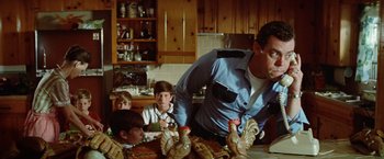 Movie still from “Brewster McCloud” (1970), directed by Robert Altman – A group of people sitting around a table with chickens; Medium shot, Low angle