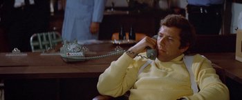 Movie still from “Brewster McCloud” (1970), directed by Robert Altman – A man sitting at a table talking on a phone; Medium shot, Low angle