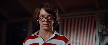 Movie still from “Brewster McCloud” (1970), directed by Robert Altman – A young man wearing a striped shirt and round glasses; Close Up shot, Low angle