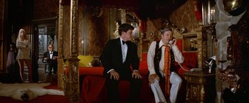 Movie still from “Brewster McCloud” (1970), directed by Robert Altman – A man and a woman sitting on a red couch; Wide shot, Low angle
