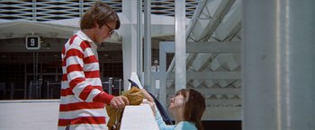 Movie still from “Brewster McCloud” (1970), directed by Robert Altman – A boy and a girl are handing clothes to each other; Medium shot, Low angle