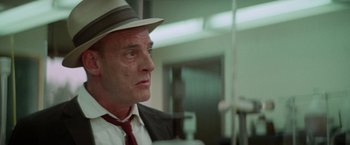 Movie still from “Brewster McCloud” (1970), directed by Robert Altman – A person wearing a suit and hat; Close Up shot, Low angle