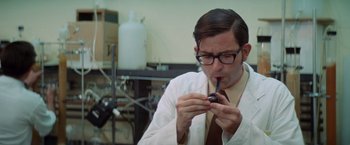Movie still from “Brewster McCloud” (1970), directed by Robert Altman – A man in a lab coat and tie holding a pipe; Medium shot, Low angle