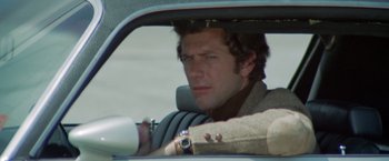 Movie still from “Brewster McCloud” (1970), directed by Robert Altman – A man sitting in the driver's seat of a car; Close Up shot, Low angle