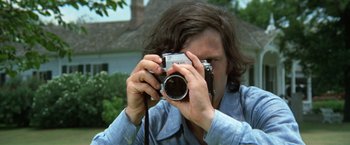 Movie still from “Brewster McCloud” (1970), directed by Robert Altman – A person taking a picture with a camera; Close Up shot, High angle