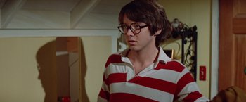 Movie still from “Brewster McCloud” (1970), directed by Robert Altman – A young man wearing a striped shirt and glasses; Close Up shot, Over the shoulder angle