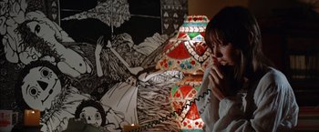 Movie still from “Brewster McCloud” (1970), directed by Robert Altman – A woman standing in front of a wall covered in pictures; Medium shot, High angle