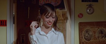 Movie still from “Brewster McCloud” (1970), directed by Robert Altman – A woman with red lipstick smiles while brushing her brown hair; Close Up shot, Over the shoulder angle