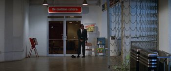 Movie still from “Brewster McCloud” (1970), directed by Robert Altman – A man standing in front of a door way; Wide shot, Low angle