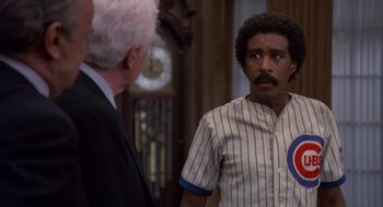 Movie still from “Brewster's Millions” (1985), directed by Walter Hill – A man in a baseball uniform talking to a man in a business suit; Medium shot, Over the shoulder angle
