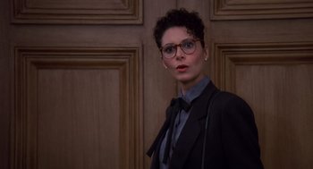 Movie still from “Brewster's Millions” (1985), directed by Walter Hill – A woman wearing a suit and tie standing in front of a door; Close Up shot, Low angle