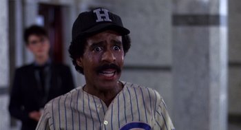 Movie still from “Brewster's Millions” (1985), directed by Walter Hill – A man with a baseball uniform and a hat on; Close Up shot, High angle