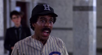 Movie still from “Brewster's Millions” (1985), directed by Walter Hill – A man with a baseball cap and a baseball jersey on; Close Up shot, Over the shoulder angle