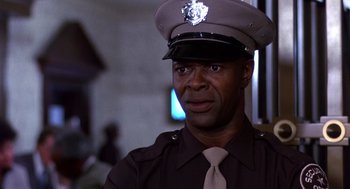 Movie still from “Brewster's Millions” (1985), directed by Walter Hill – A man in a police uniform is looking at the camera; Close Up shot, Low angle