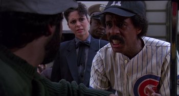 Movie still from “Brewster's Millions” (1985), directed by Walter Hill – A group of people standing around each other in a room; Medium shot, Over the shoulder angle