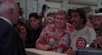 Movie still from “Brewster's Millions” (1985), directed by Walter Hill – A group of people sitting around a table; Medium shot, Over the shoulder angle