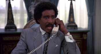 Movie still from “Brewster's Millions” (1985), directed by Walter Hill – A man talking on a phone while sitting in a chair; Close Up shot, High angle
