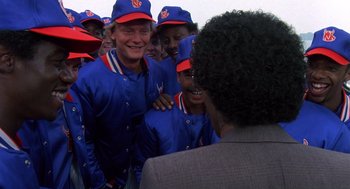 Movie still from “Brewster's Millions” (1985), directed by Walter Hill – A group of baseball players are laughing together; Medium shot, Over the shoulder angle