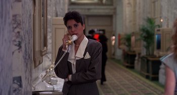 Movie still from “Brewster's Millions” (1985), directed by Walter Hill – A woman talking on a phone while standing next to a counter; Medium shot, Low angle