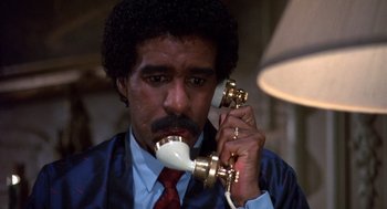 Movie still from “Brewster's Millions” (1985), directed by Walter Hill – A man holding a phone up to his ear while wearing a tie; Close Up shot, High angle