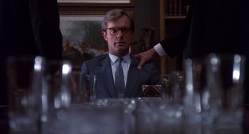 Movie still from “Brewster's Millions” (1985), directed by Walter Hill – A man sitting at a dinner table with a glass of wine; Close Up shot, Over the shoulder angle